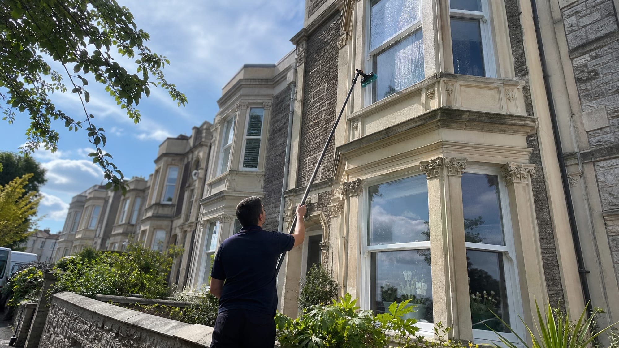 Darren cleaning the upstairs windows of a Bristol home from the ground with a water-fed pole
