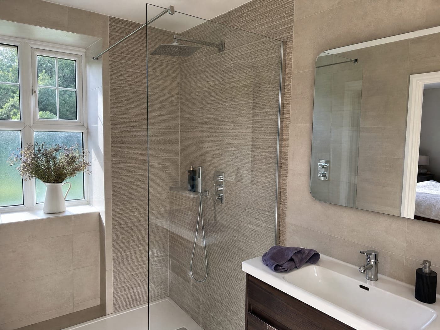 A spotless frameless glass shower screen and mirror in a bright Bristol bathroom