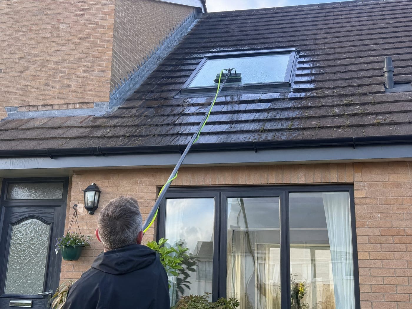 A water-fed pole cleaning a roof skylight on a Bristol house from the ground